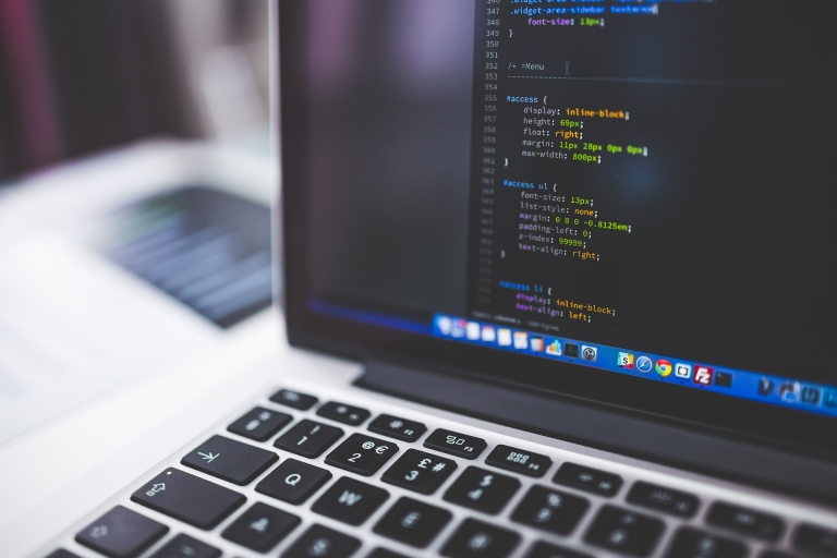 Laptop open with text editor on screen writing CSS